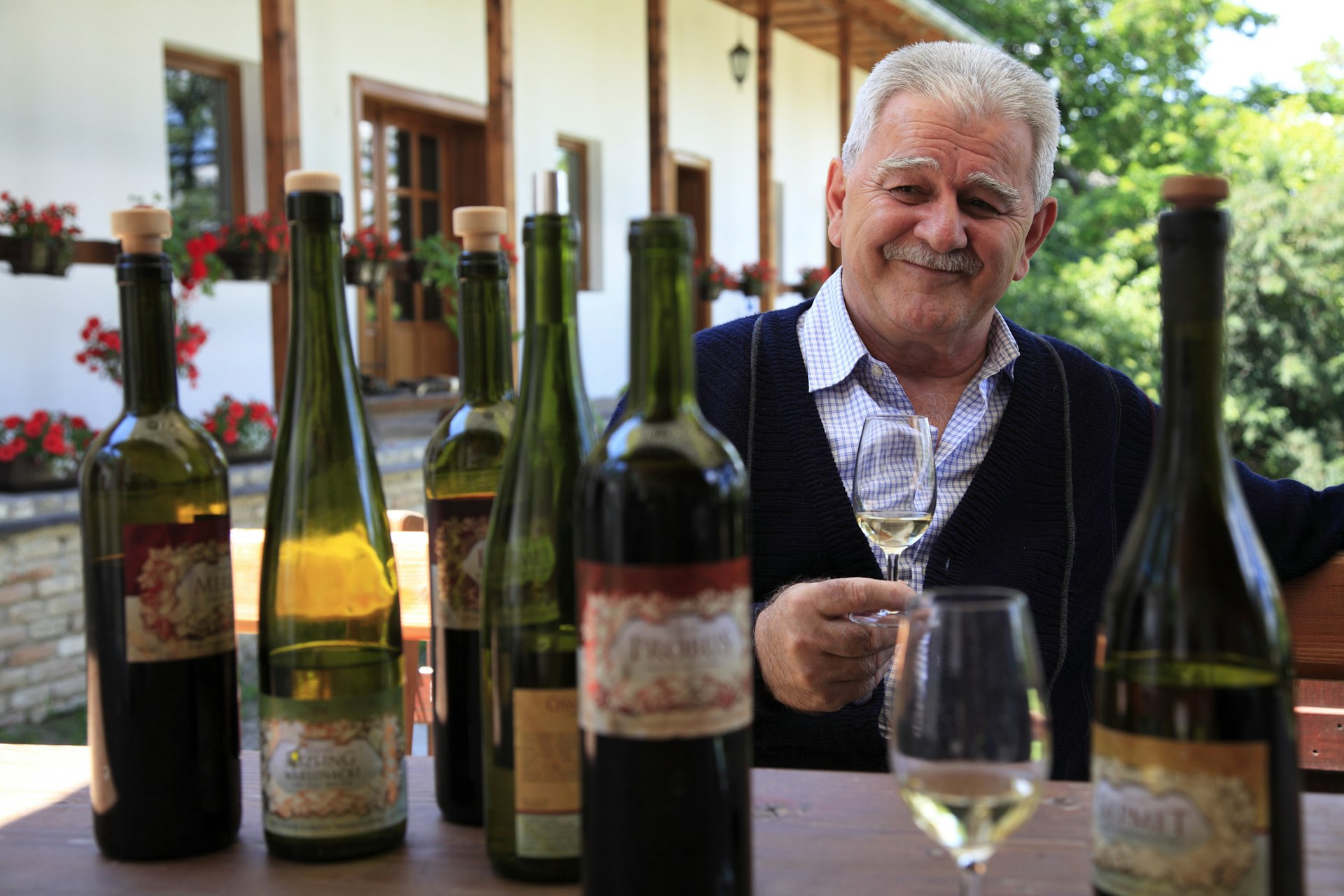 A wine maker sits in front of several bottles of wine as he hosts a wine tasting