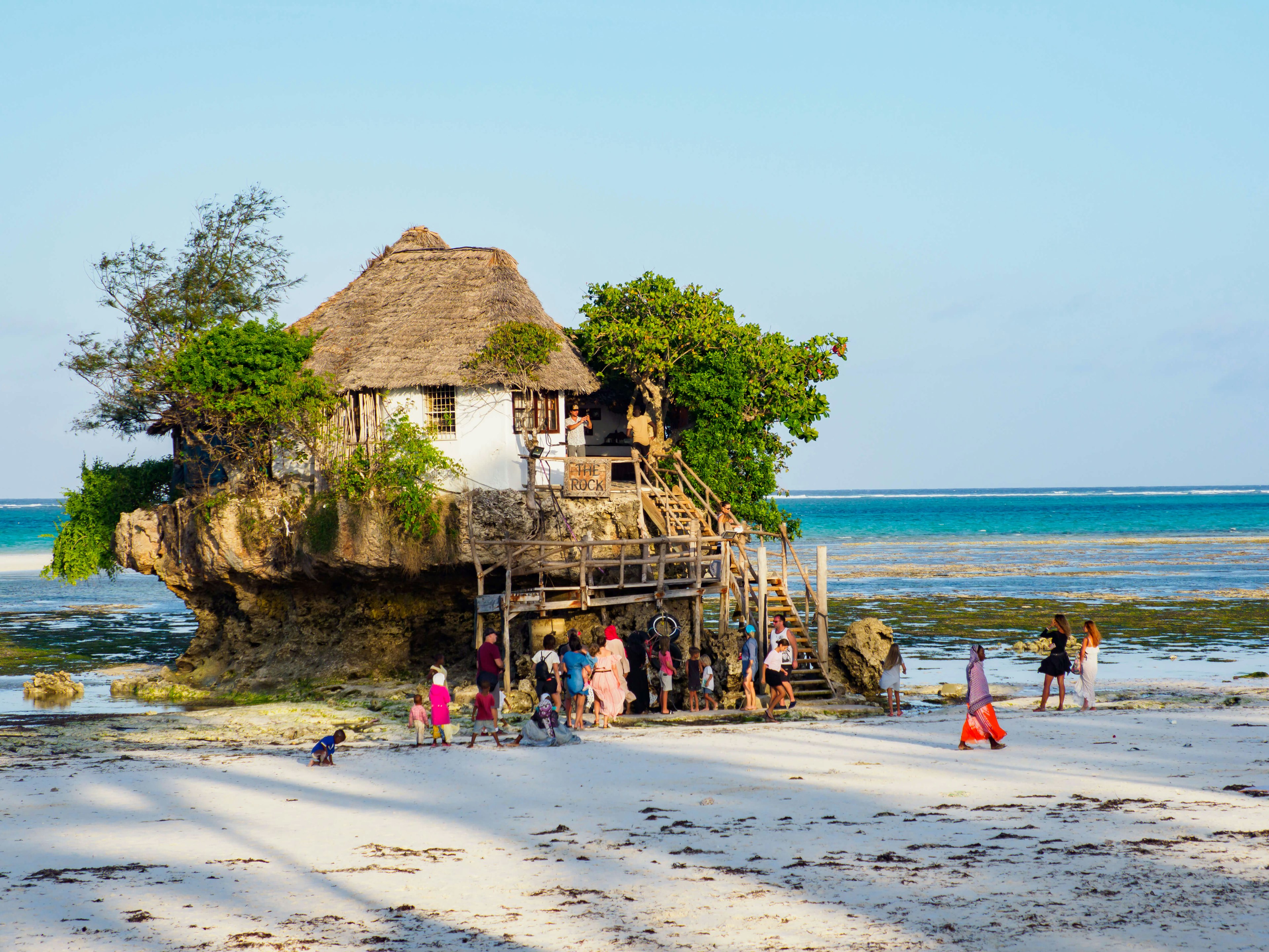 People gathered in front of the Rock, a restaurant built on the cliff in the sea by Pingwe Beach in Zanzibar