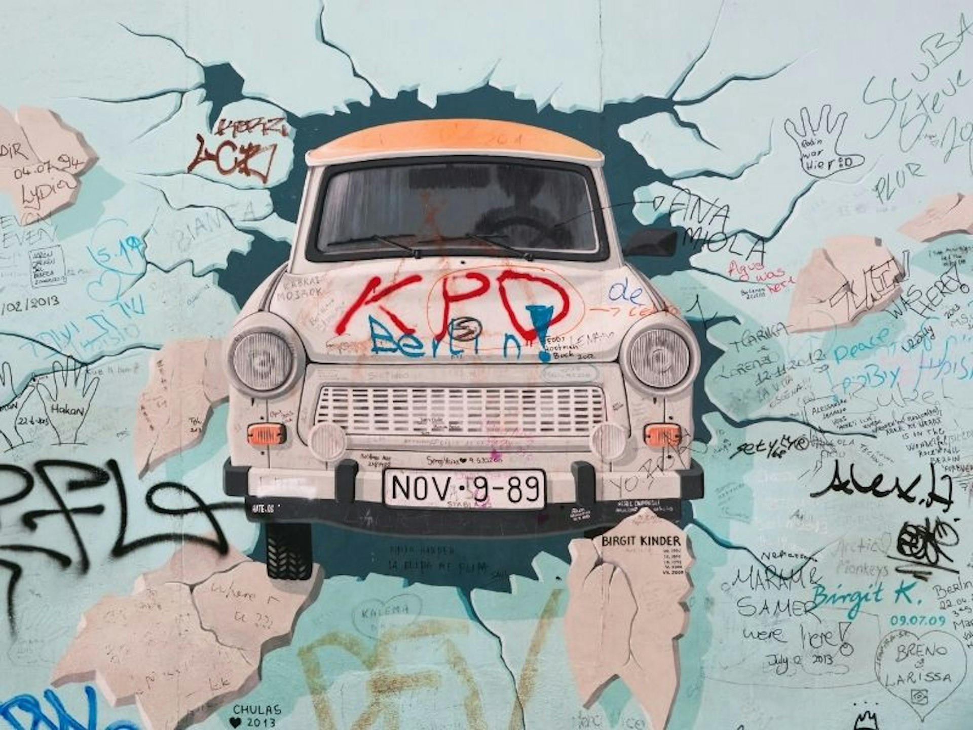 Image of a car bursting through a wall at the East Side Gallery in Berlin
