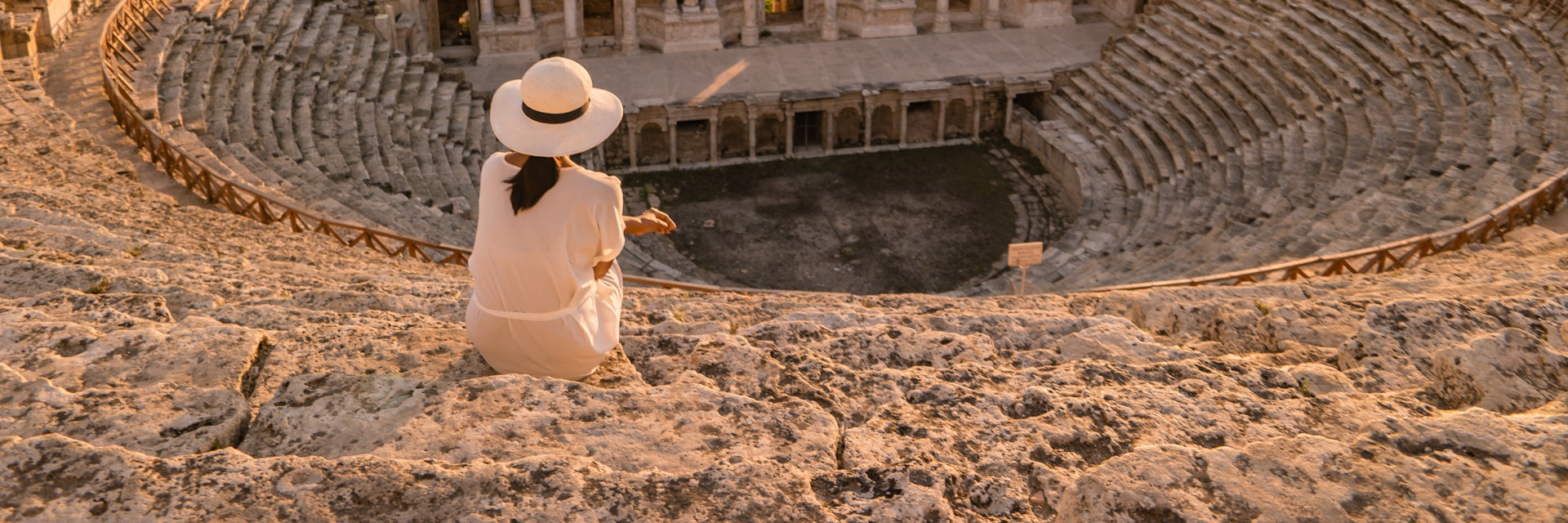 Hierapolis ancient city Pamukkale Turkey, young woman with hat watching sunset by the ruins Unesco ; Shutterstock ID 1167278944; your: Bridget Brown; gl: 65050; netsuite: Online Editorial; full: POI Image Update