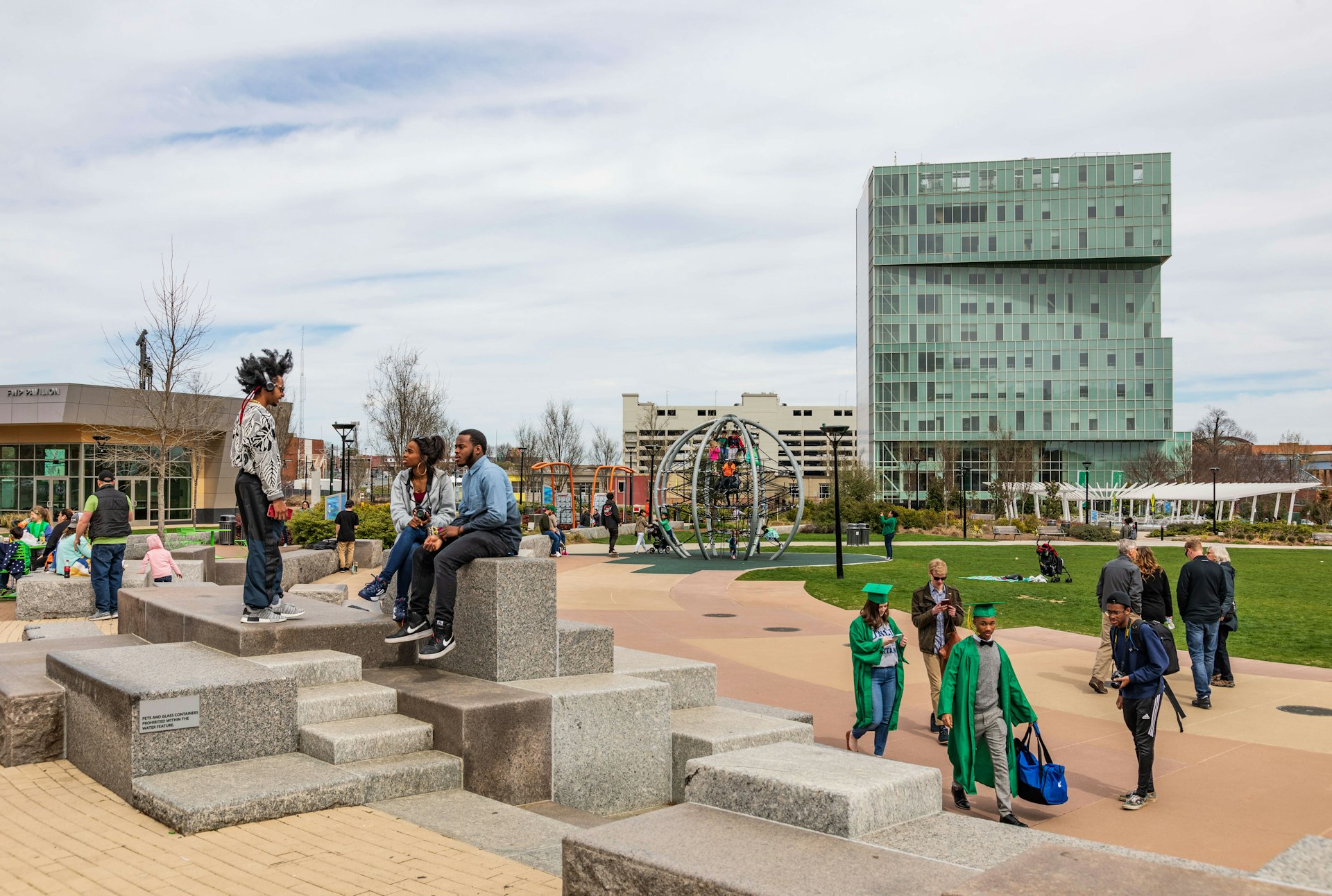 A diverse crowd of people in Charlotte's First Ward Park on a sunny spring day