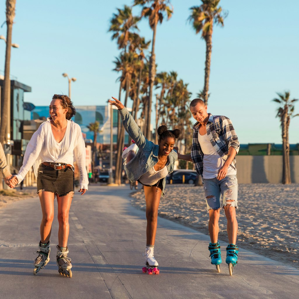 Friends roller skating on the boardwalk in Venice Beach - Santa Monica promenade - Los Angeles, USA
