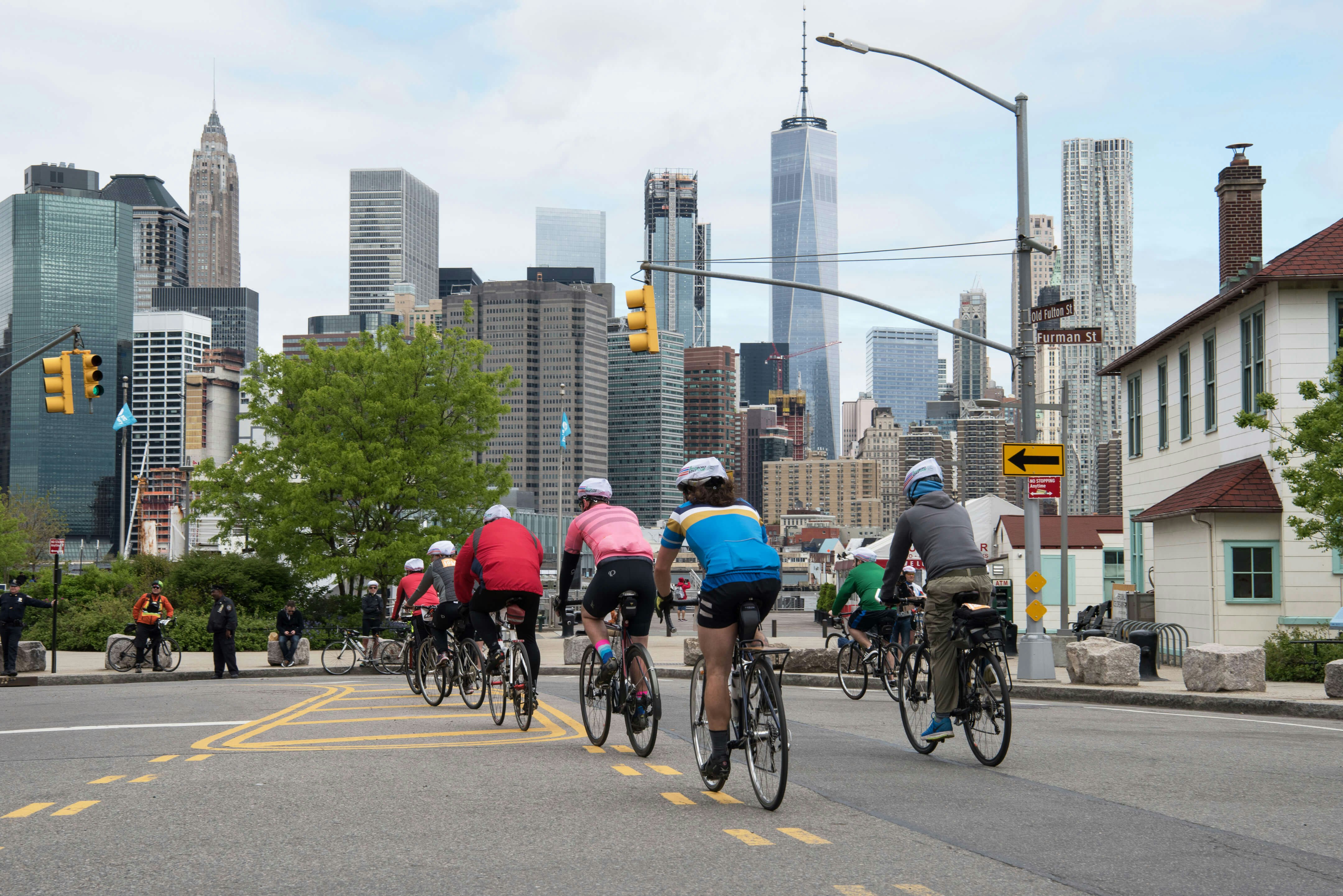 Cyclists riding in the Five Boro Bike Tour with the Manhattan skyline in the background