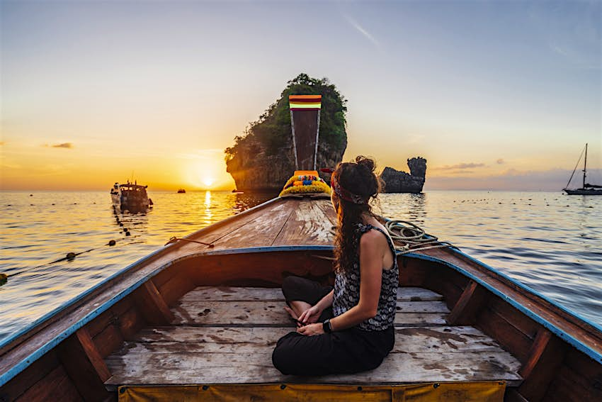 Wanita muda di perahu ekor panjang di Thailand saat matahari terbenam, Pulau Phi Phi