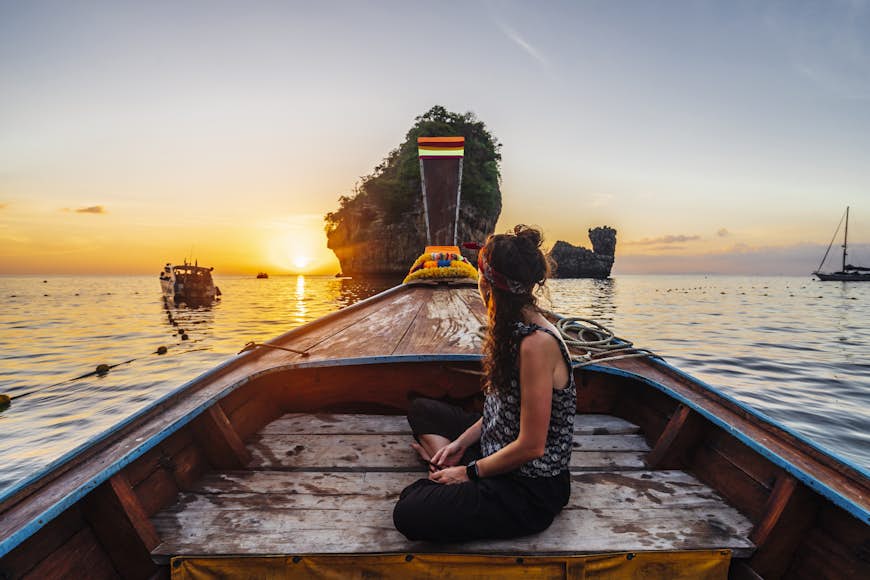 Young woman on a longtail boat in Thailand during sunset, Phi Phi Island