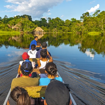 Transport in canoe along the rivers of the Amazon River Basin inside the Yasuni National Park with a view of a lodge in traditional style, Ecuador.