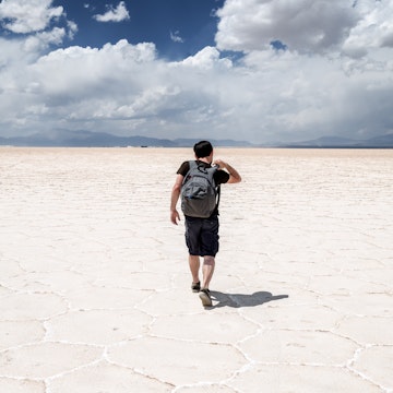 Salinas Grandes, Jujuy, Argentina - October 13, 2019: Young man walking with his backpack on the salt flats in the Salinas Grandes in Jujuy, Argentina