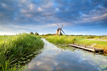 Dutch windmill and blue morning sky reflected in river near Grogingen, Netherlands