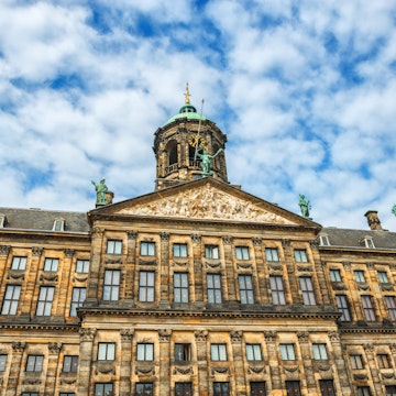 The Royal Palace in Amsterdam is situated in the west side of Dam Square in the centre of Amsterdam, Holland. Beautiful blue sky with cloudscape over the palace. The Netherlands.