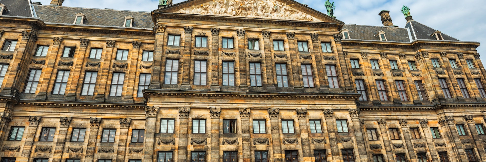 The Royal Palace in Amsterdam is situated in the west side of Dam Square in the centre of Amsterdam, Holland. Beautiful blue sky with cloudscape over the palace. The Netherlands.