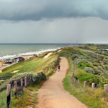 The Westkapelse Zeedijk forms part of the dutch coastal flood defense system. This modern dike, with a layer of basalt stones covered with sand and grass, protects he whole island of Walcheren against coastal floods. Modern flood protection measures allow for recreational and economic activities and development of a natural environment. Picture is taken on a stormy day in summer when a thunderstorm is approaching.