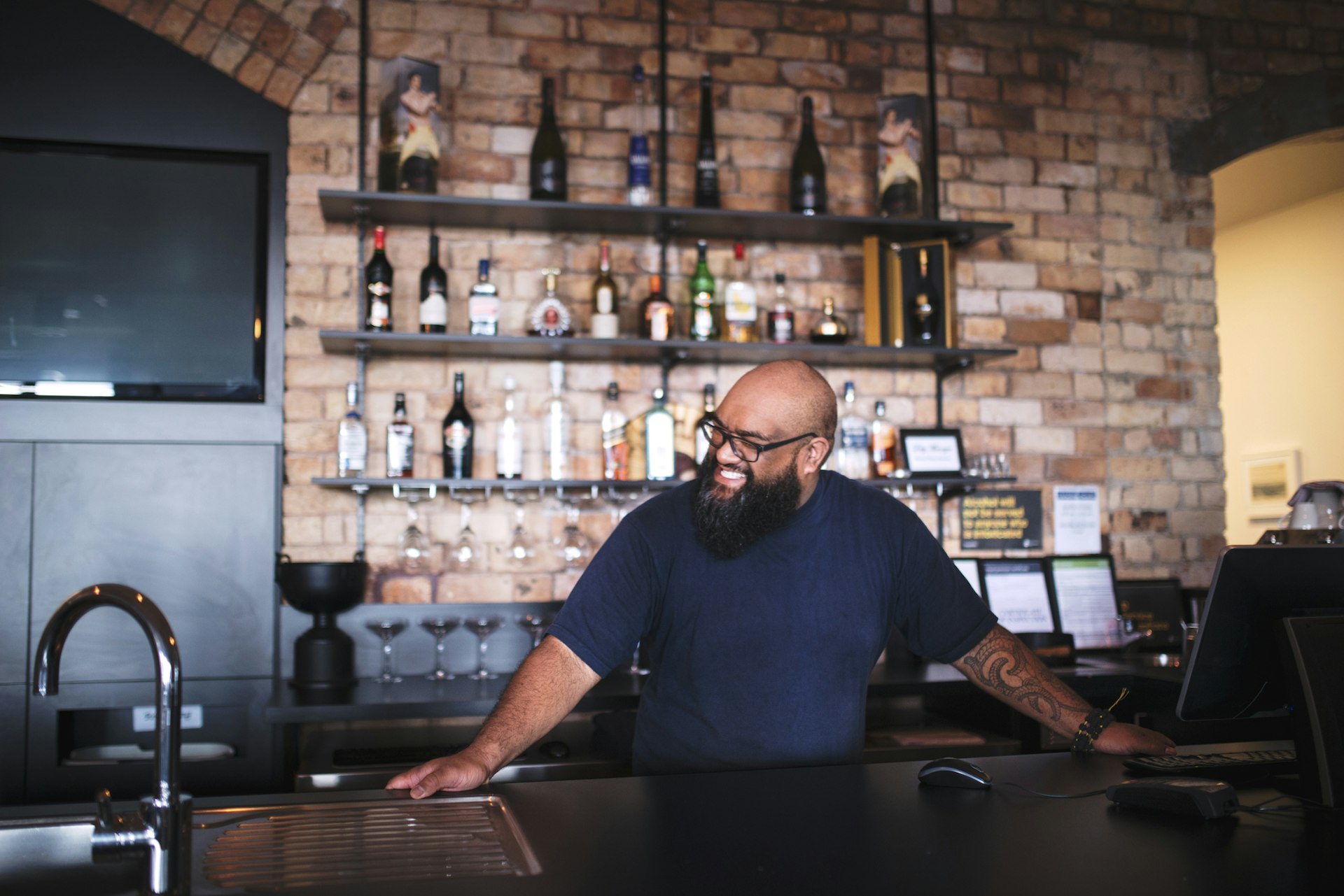 A man smiles as he stands behind a bar in a pub
