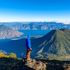 Hiker with panorama view of Lake Atitlan and volcano San Pedro and Toliman early in the morning from peak of volcano Atitlan, Guatemala. Hiking and climbing on Vulcano Atitlan.