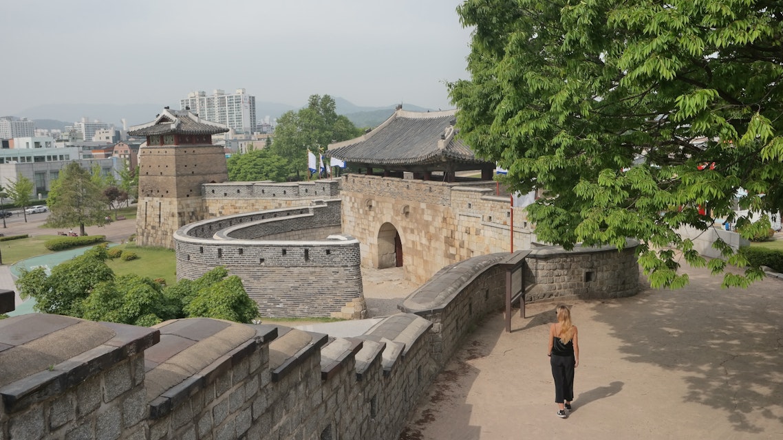 A woman walks along the walls of Hwaseong Fortress.