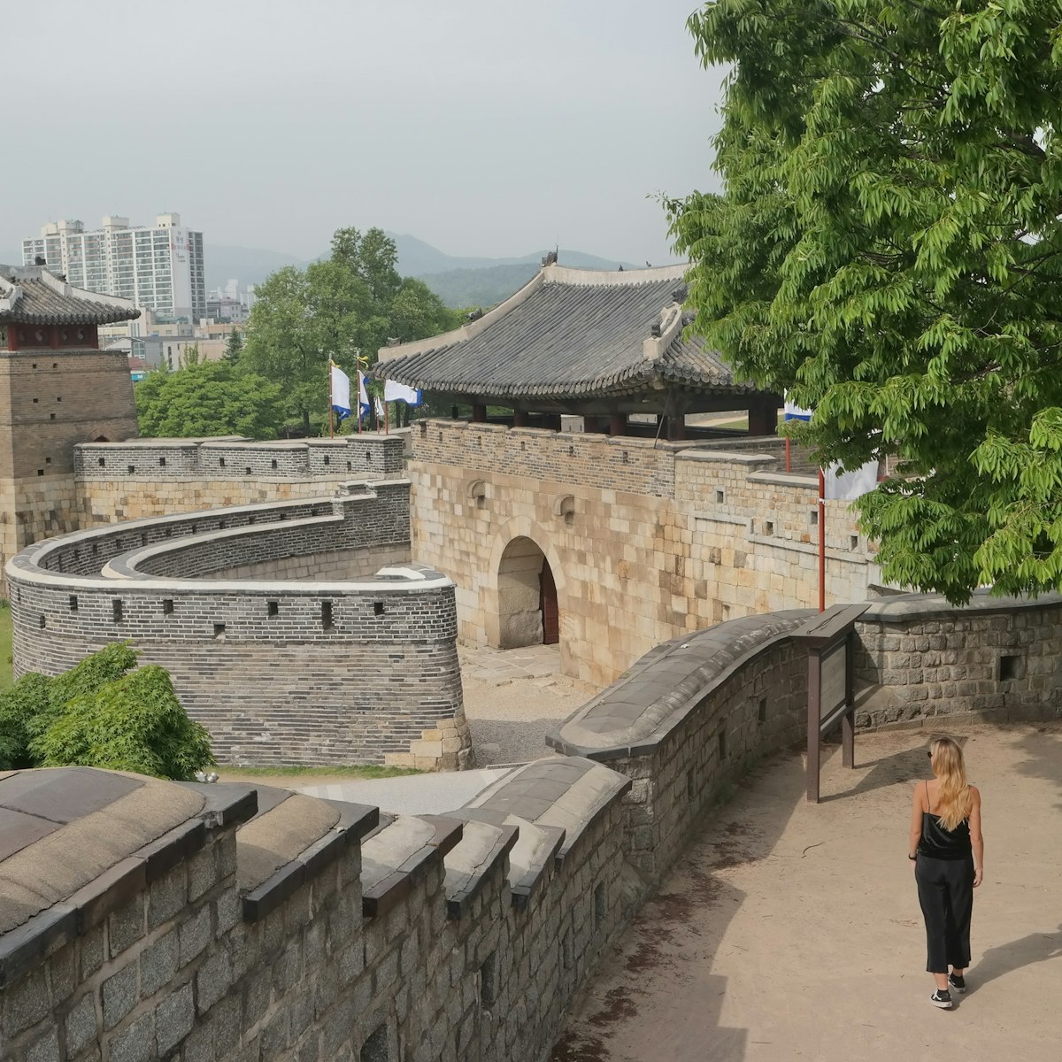 A woman walks along the walls of Hwaseong Fortress.