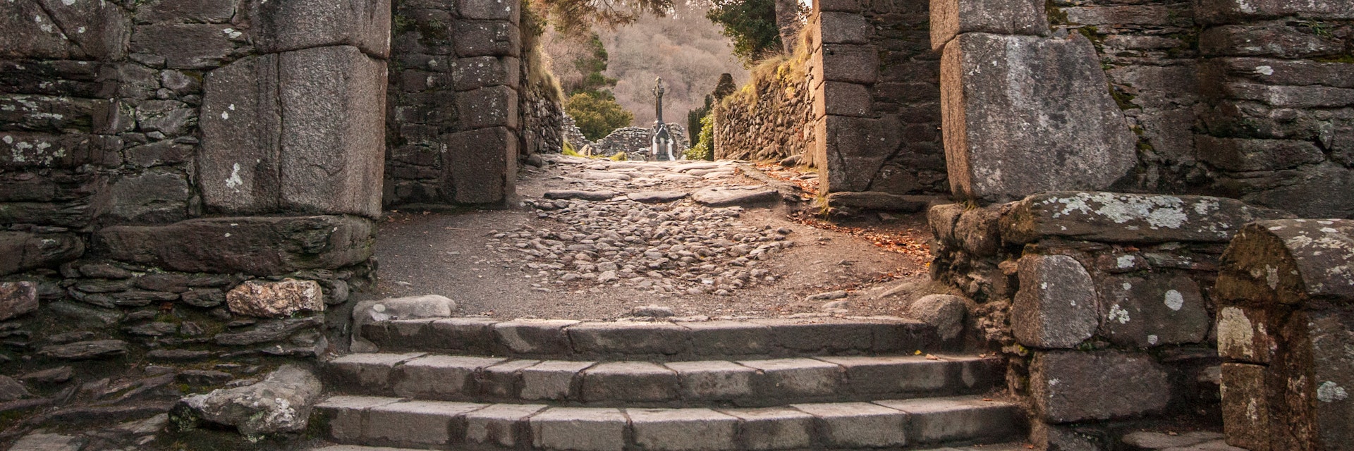 Stone arches and walls with stairs leading to Celtic cross.