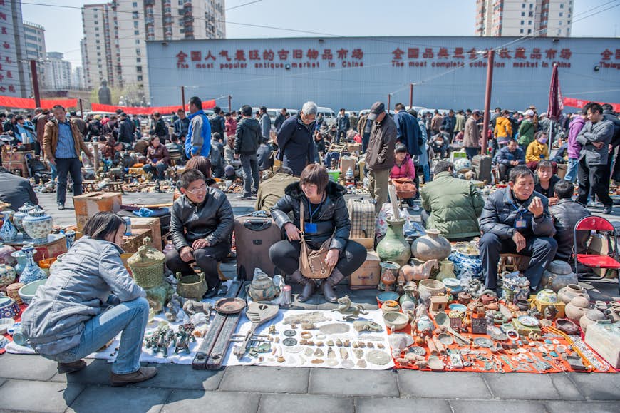 Människor samlas framför försäljare på Panjiayuan-marknaden i Peking