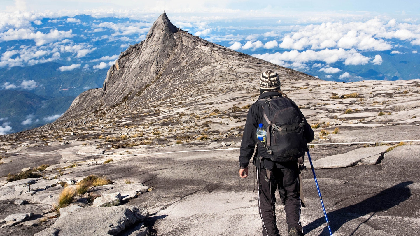 Hiker at the top of Mount Kinabalu in Sabah, East Malaysia. The climb to the summit of Mount Kinabalu is one of Sabah's most popular tourist attractions.