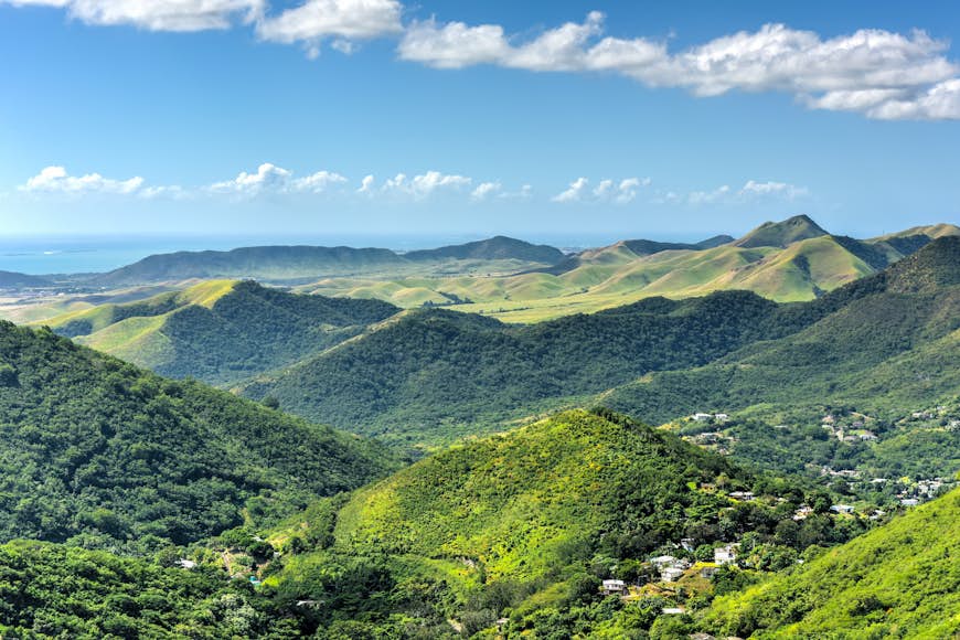 Landskapsvy frodiga tropiska kullar mot en blå himmel med havet i fjärran nära Salinas, Puerto Rico