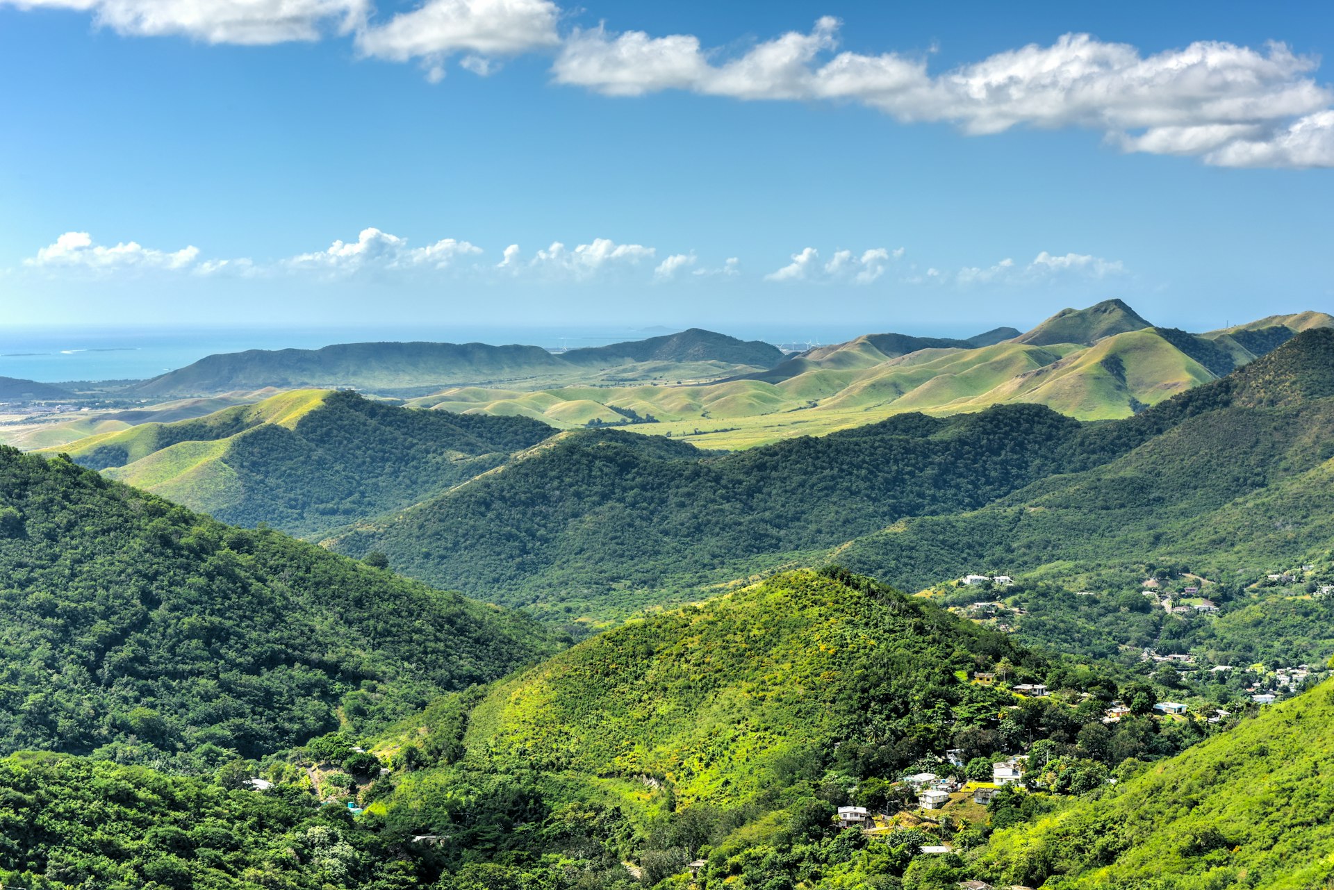 Landscape view of lush tropical hills against a blue sky with the sea in the distance near Salinas, Puerto Rico