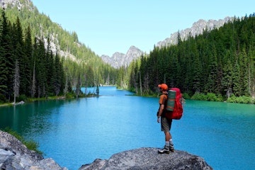 Man backpacker by lake. Nada lake, Enchantment Lakes basin, Leavenworth, Washington state, USA.