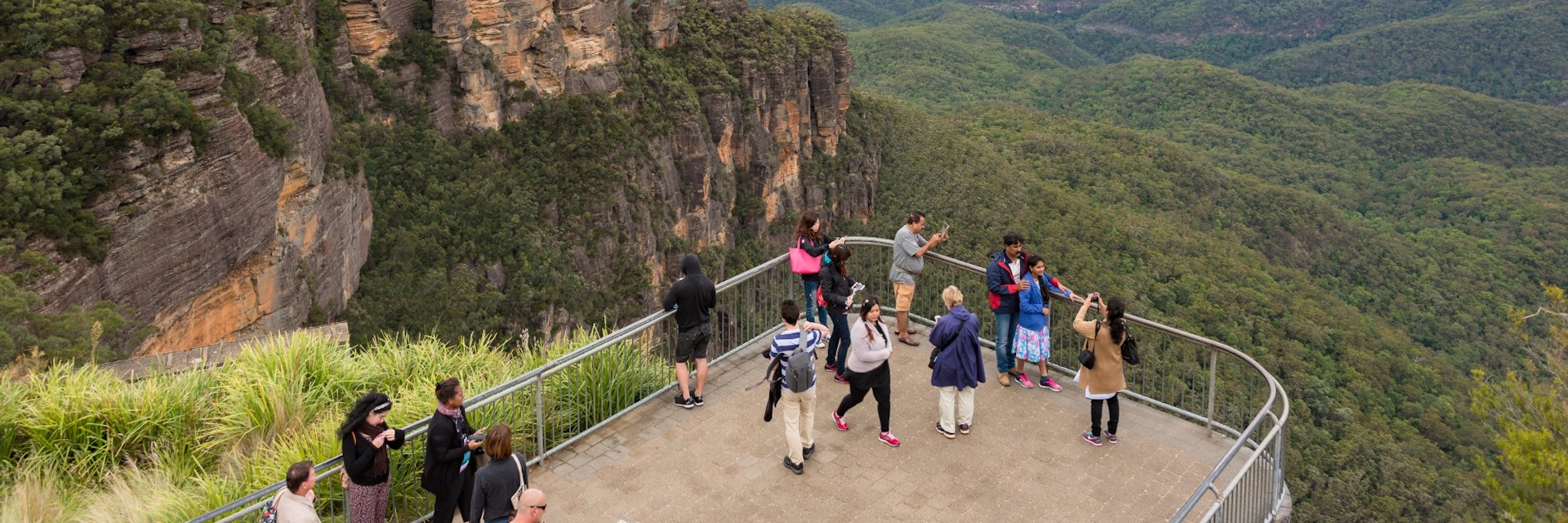 Blue Mountains, Australia - May 1, 2016: People at observation deck at Echo point lookout with view of famous Three Sisters mountains and Blue Mountains eucalyptus forest