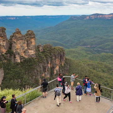 Blue Mountains, Australia - May 1, 2016: People at observation deck at Echo point lookout with view of famous Three Sisters mountains and Blue Mountains eucalyptus forest