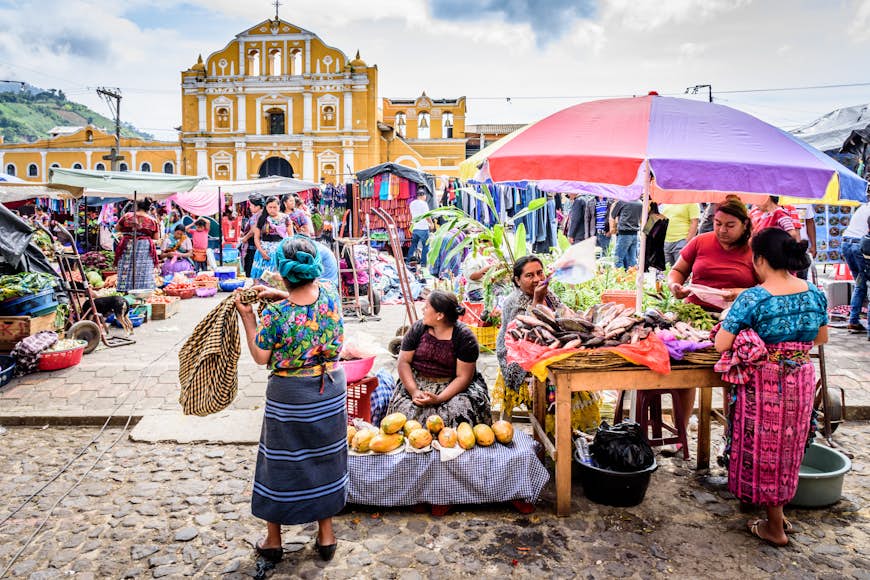 A Colorful Sunday produce market in front of pastel-colored cathedral facade in Antigua, Guatemala