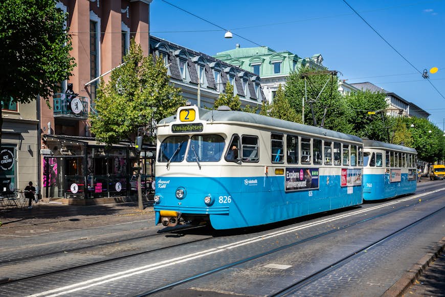 A blue-and-white electric tram pulls in to a tram stop in Gothenburg, Sweden