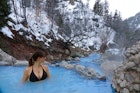 CLOSE UP: Female traveler relaxes in the soothing hot water of Fifth Water Springs in Utah. Young Caucasian woman in a black bikini stands in a stunning turquoise pond and observes the snowy nature.; Shutterstock ID 1539628718; your: Brian Healy; gl: 65050; netsuite: Online Editorial; full: Best free things to do in Utah