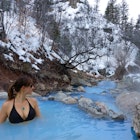 CLOSE UP: Female traveler relaxes in the soothing hot water of Fifth Water Springs in Utah. Young Caucasian woman in a black bikini stands in a stunning turquoise pond and observes the snowy nature.; Shutterstock ID 1539628718; your: Brian Healy; gl: 65050; netsuite: Online Editorial; full: Best free things to do in Utah