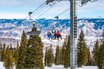Skiers and snowboarders ascend the Alpine Springs chairlift at the Aspen Snowmass ski resort, in the Rocky Mountains of Colorado on a partly cloudy winter day. 