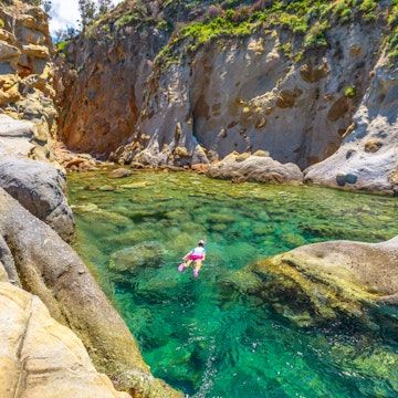 Top view of snorkeler in Sant 'Andrea beach Cote Piane side with rocks and coves, Elba island. Woman in clear waters of Tyrrhenian sea on holiday travel, Italy. Saint Andrew is popular seaside resort.