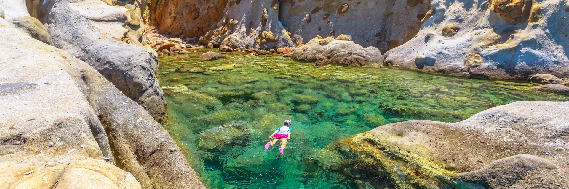 Top view of snorkeler in Sant 'Andrea beach Cote Piane side with rocks and coves, Elba island. Woman in clear waters of Tyrrhenian sea on holiday travel, Italy. Saint Andrew is popular seaside resort.