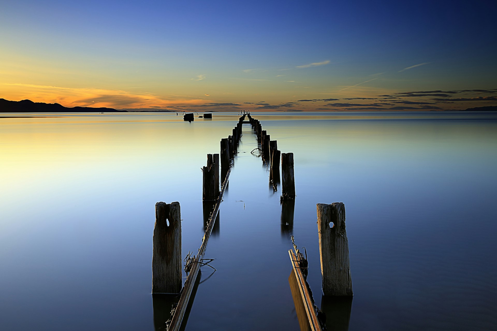 Blue, orange and gold light of sunset reflected by a pier on the Great Salt Lake