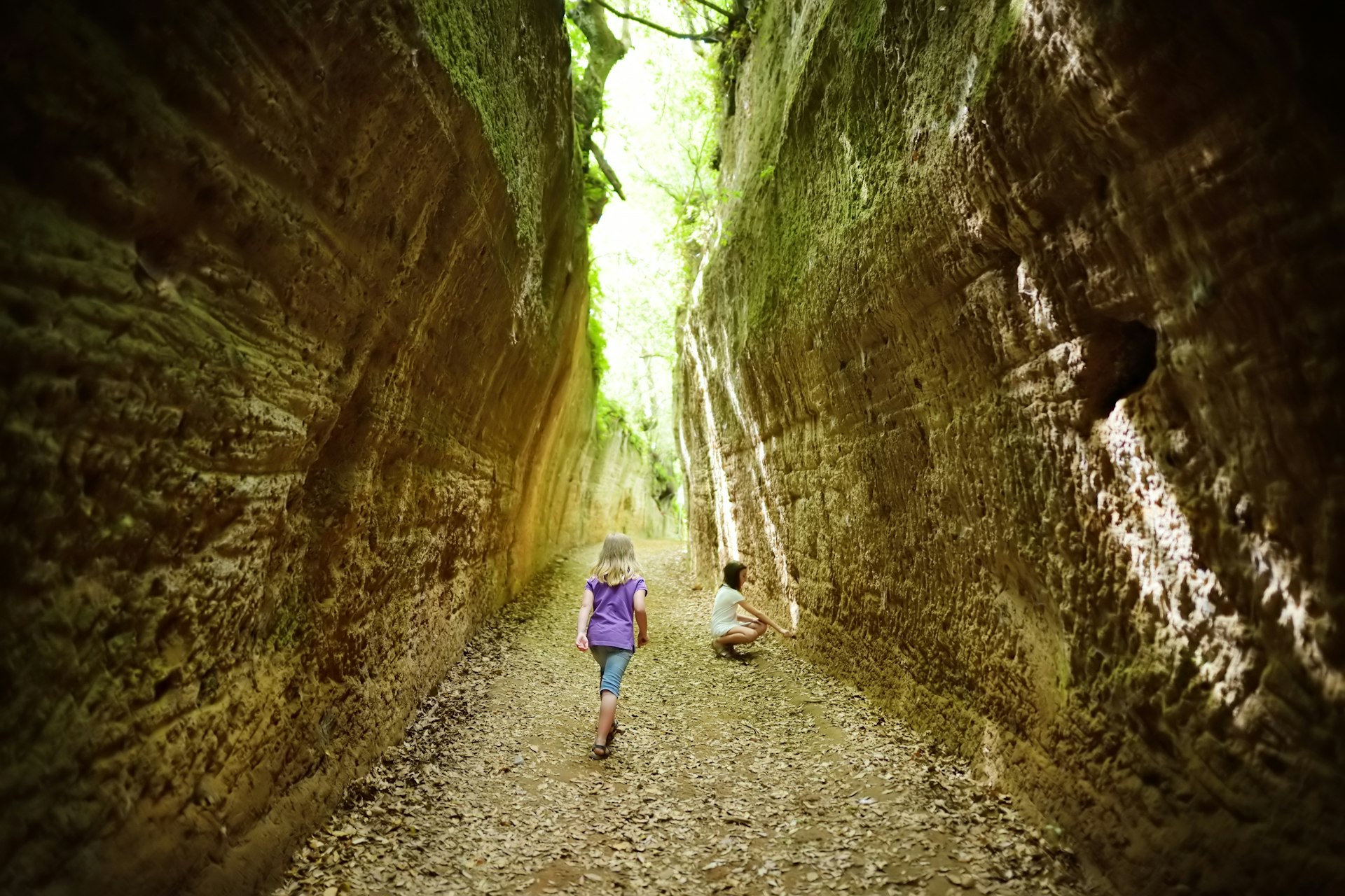 Children wander down the vie cave, excavated ancient Etruscan roads at the Necropoli di Sovana