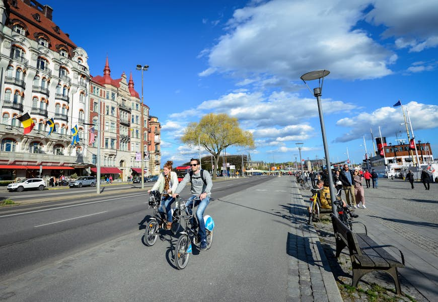 Two cyclists on a bike lane next to a waterfront walkway in Stockholm, Sweden