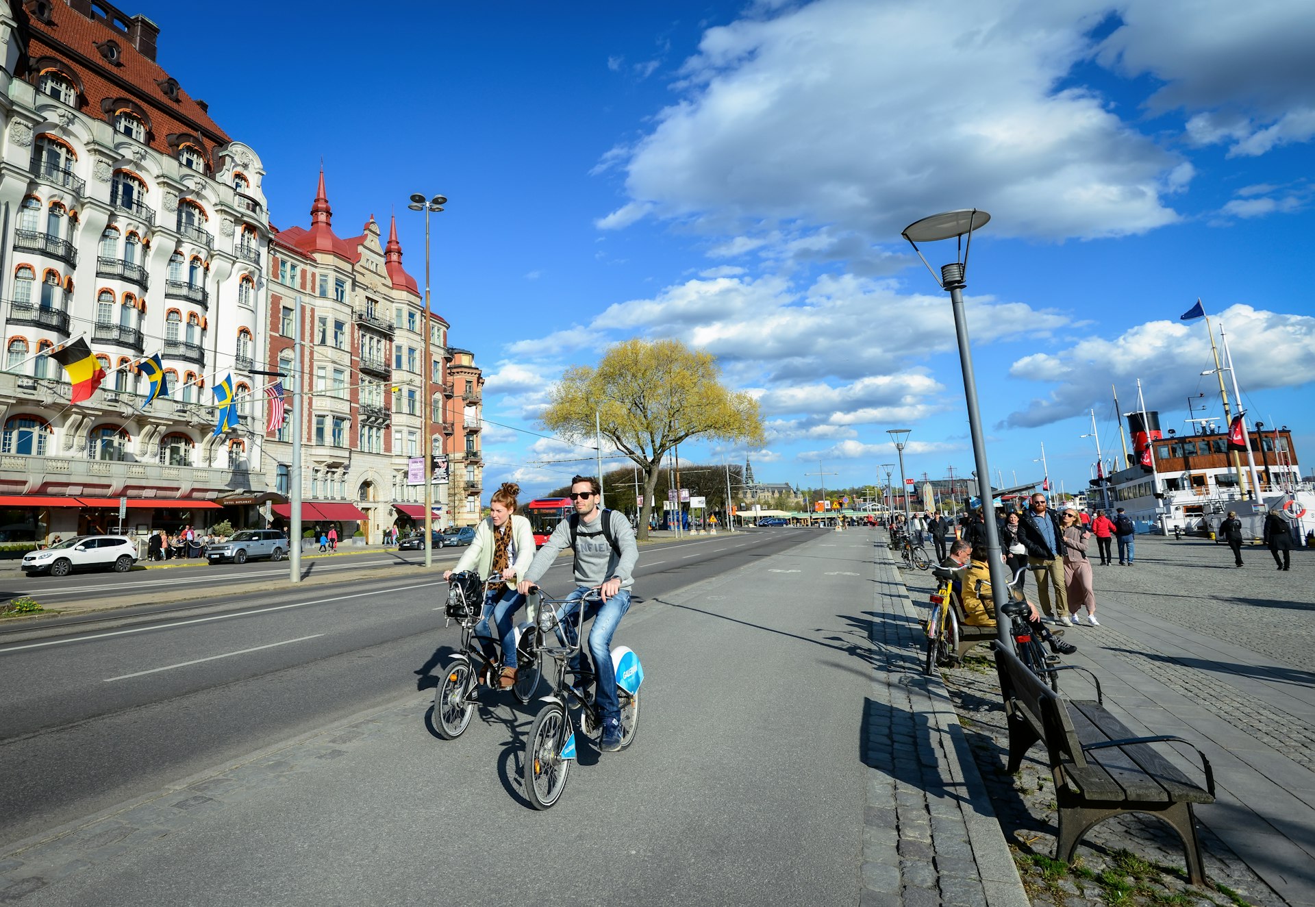 Two bicyclists on a bike path next to a pedestrian pathway by the waterfront in Stockholm, Sweden