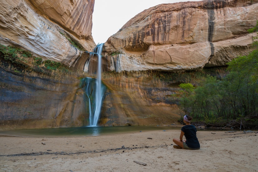 Woman Sitting in front of the Lower Calf Creek Falls, Calf Creek, Grand Staircase-Escalante National Monument, south Utah, USA; Shutterstock ID 335456882; your: Brian Healy; gl: 65050; netsuite: Online Editorial; full: Best beaches in Utah