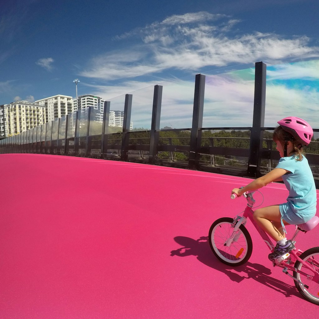 Happy young girl (age 07) ride a bike on  bright pink cycleway in Auckland, New Zealand. Real people. Copy space; Shutterstock ID 613004390; your: Brian Healy; gl: 65050; netsuite: Lonely Planet Editorial; full: Free things to do in Auckland