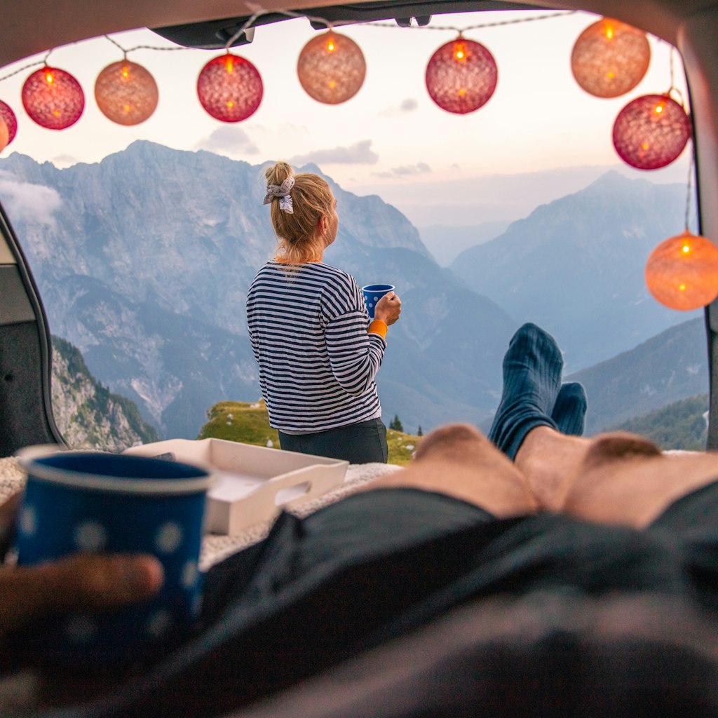 Couple camping in car with scenic view of mountain range