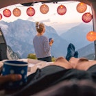 Couple camping in car with scenic view of mountain range