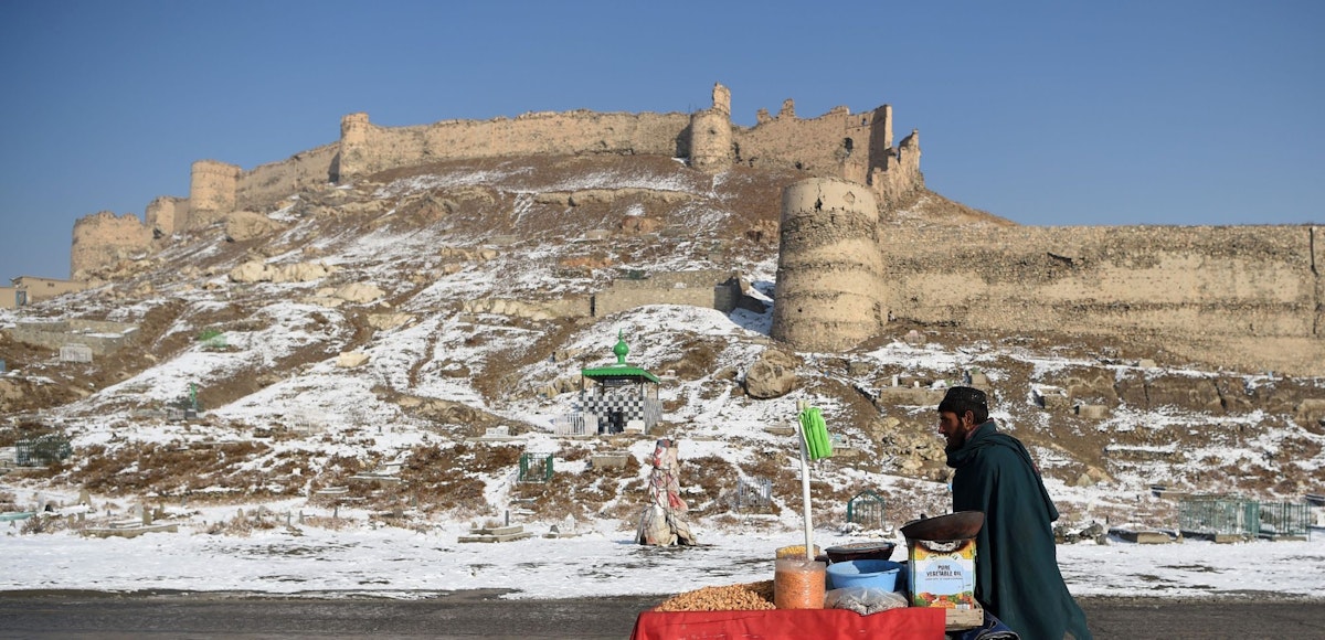TOPSHOT - An Afghan vendor pushes a wheelbarrow after the first snowfall near the old fortress of Bala Hissar in Kabul on December 15, 2017. / AFP PHOTO / WAKIL KOHSAR        (Photo credit should read WAKIL KOHSAR/AFP via Getty Images)