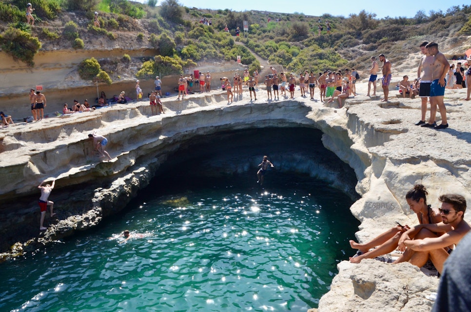 Swimmers and divers at St Peters Pool in Delimara, Malta.