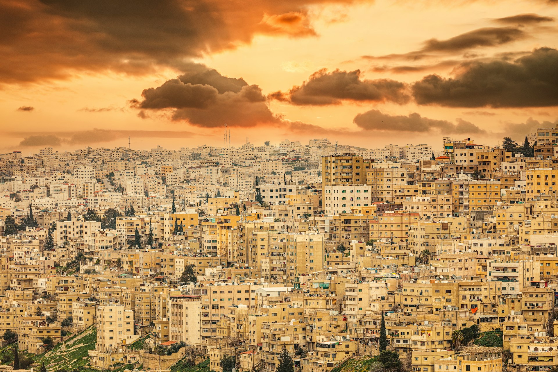 A wide view of dense apartment blocks on a hillside in Amman, Jordan, at sunset