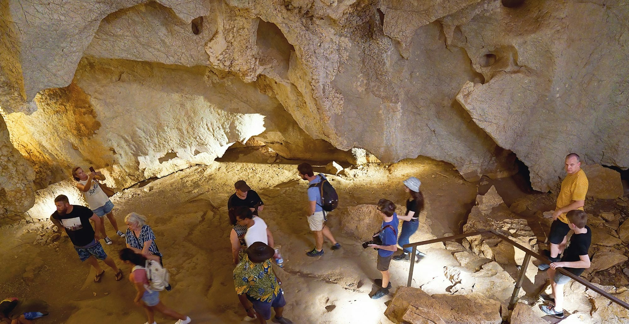 Queensland, Australia - December 2019: Tourists inside a cavern explore the ecosystem of the Capricorn Caves. Photography difficult due to very low light.