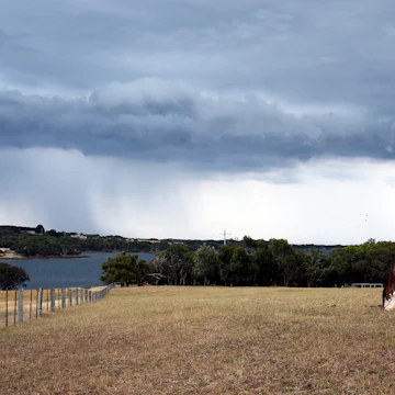 Horse eating grass on Churchill Island Heritage Farm (Victoria, Australia). Dramatic clouds and storm above Philip Island in the background. ; Shutterstock ID 556271059; your: Bridget Brown; gl: 65050; netsuite: Online Editorial; full: POI Image Update