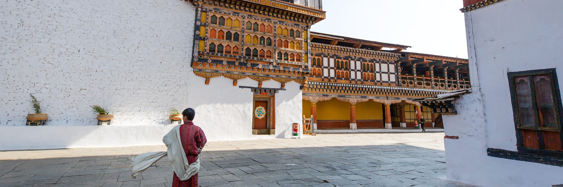 A local guide standing still while wearing a traditional clothing for men called Gho a knee length and kimono-like cloth held in place by a belt called Kera. Rinpung Dzong is an architectural feat housing a network of courtyards, temples and offices. Its full name is Rinche Pung Dzong which literally means Fortress on a Heap of Jewels.