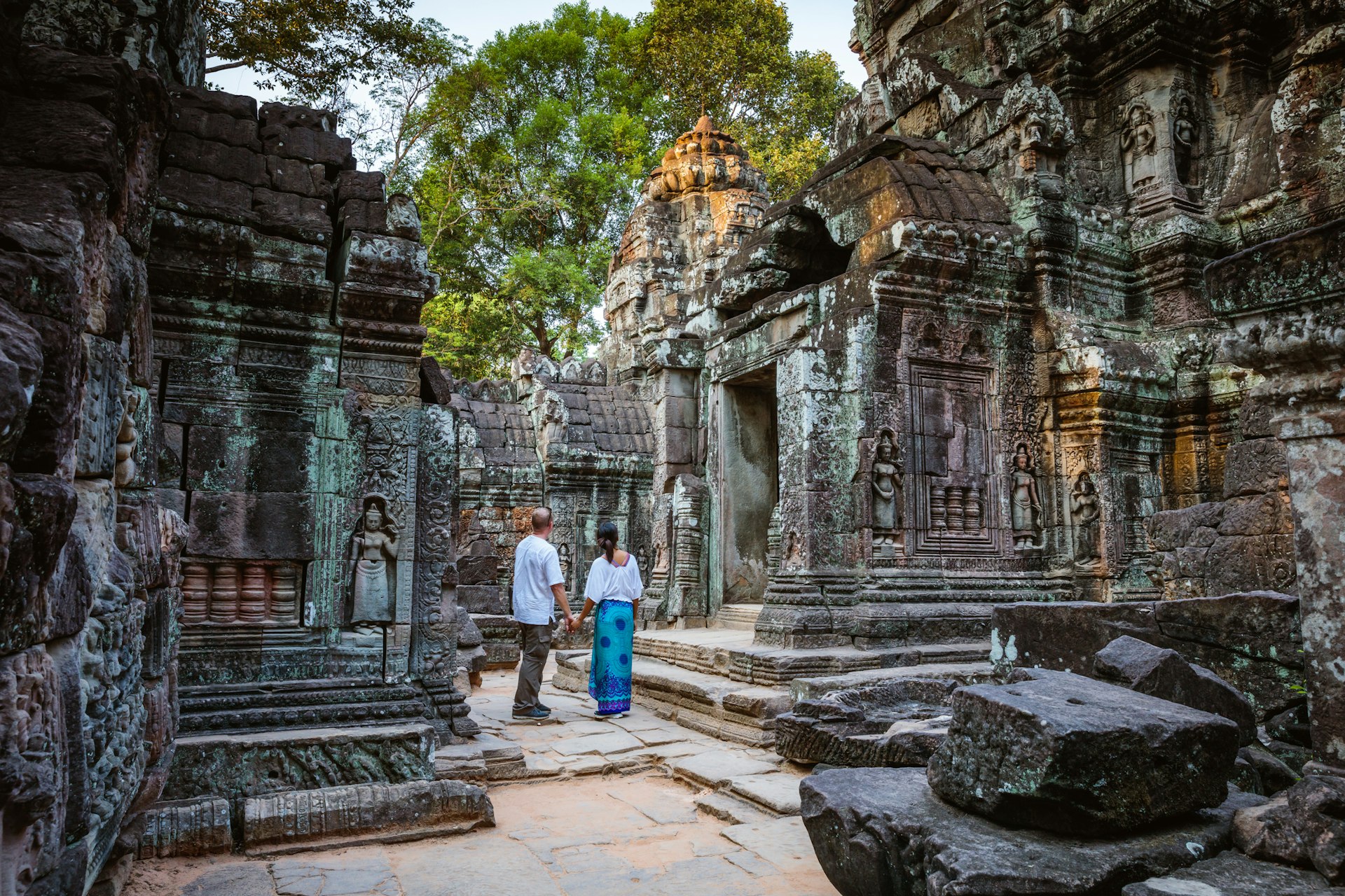 Adult couple stand looking up at the stone walls of an ancient temple