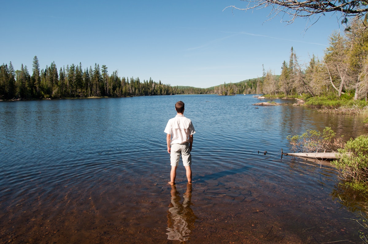 Man standing in water relaxing and contemplating wildness of lake superior provincial park, Canada.